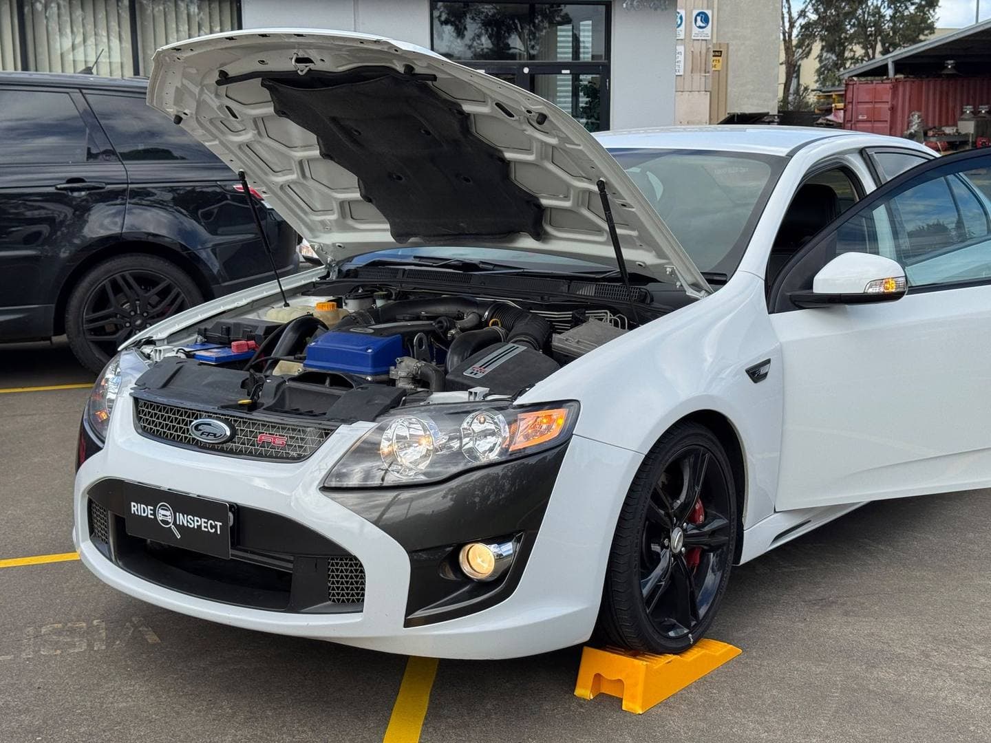 White Ford FPV sedan with the bonnet and driver's door open in a car park