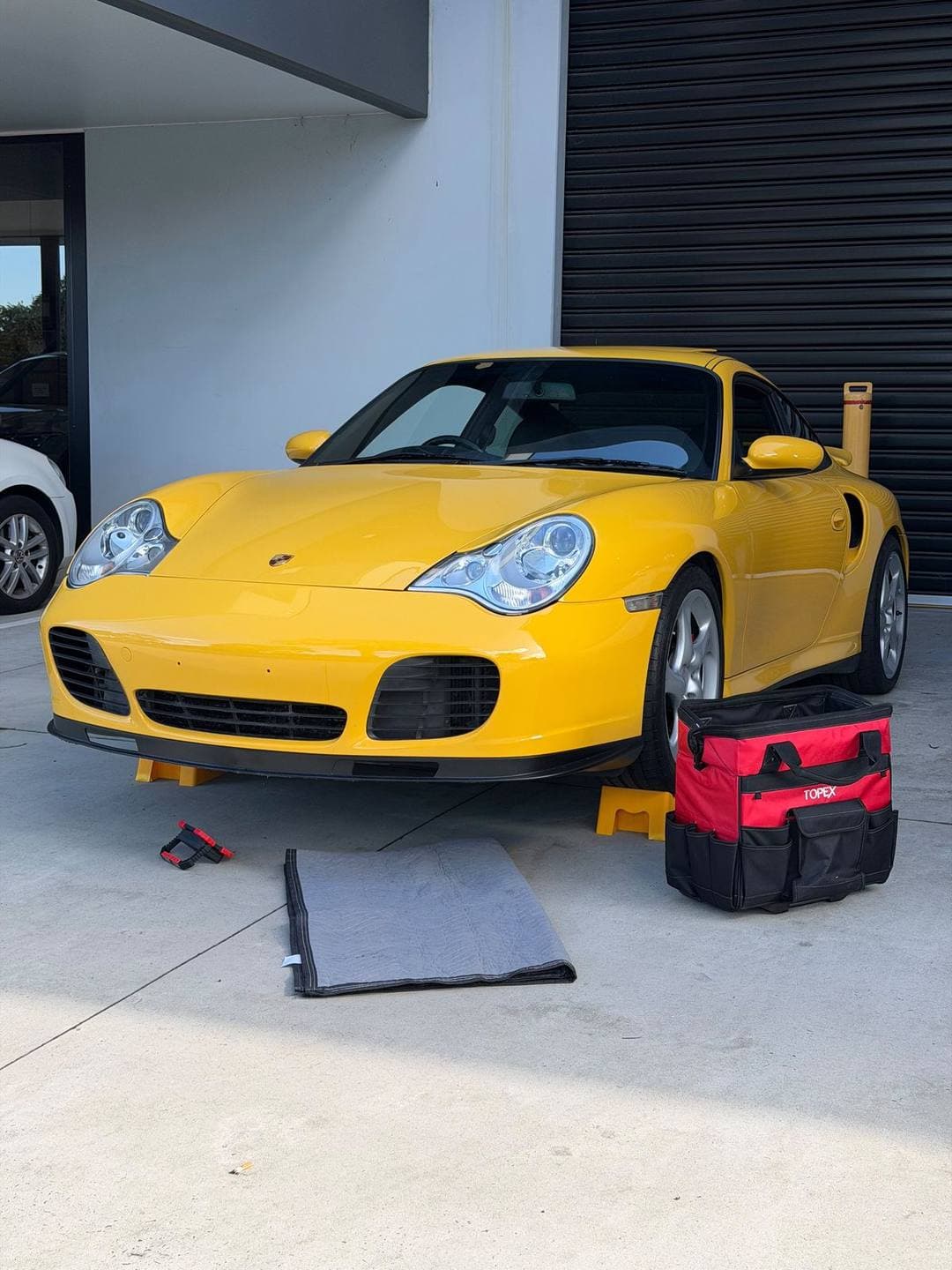 Yellow Porsche 911 Turbo (996) with the tool bag and a mat laid out in front